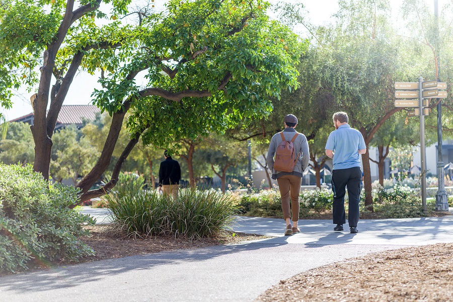 2 students walking down a sidewalk on campus