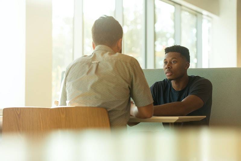 Two young men having a conversation at a table