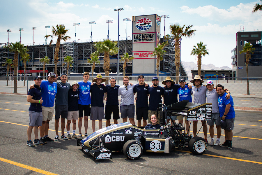 students posing by a race car