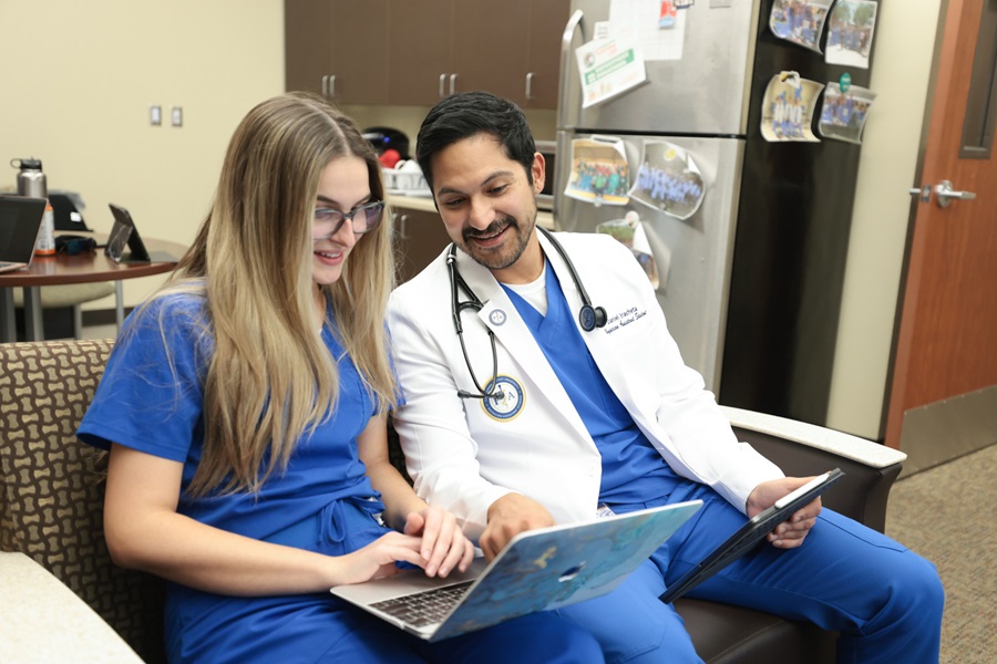 2 students working on laptop in a break room