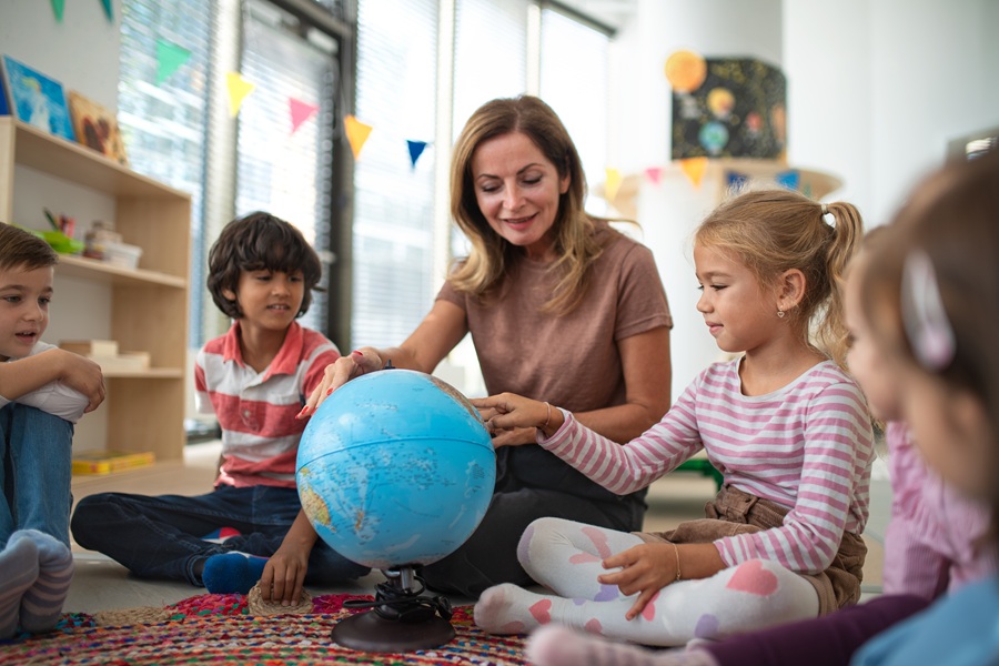 Female teacher helping students locate places on a globe