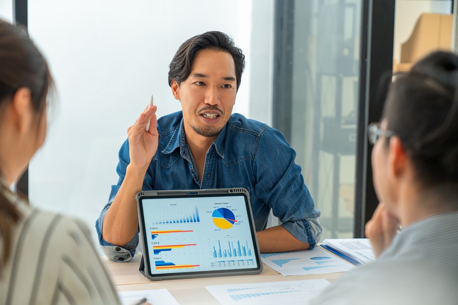 Man giving a presentation off a tablet displaying data in different graph types