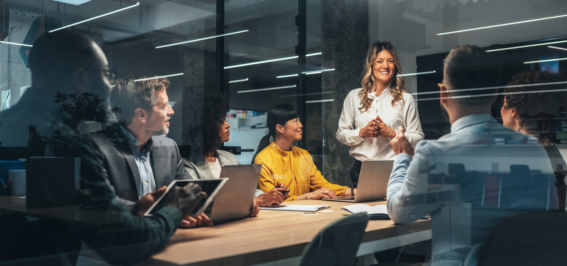 Woman presenting at a meeting table with other individuals