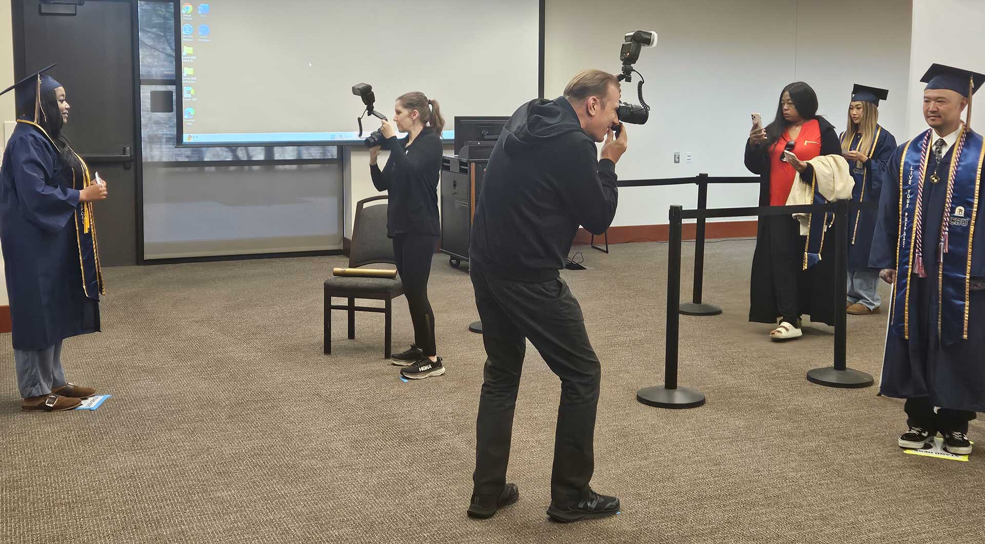 Photographers taking photos of grads in a classroom setting